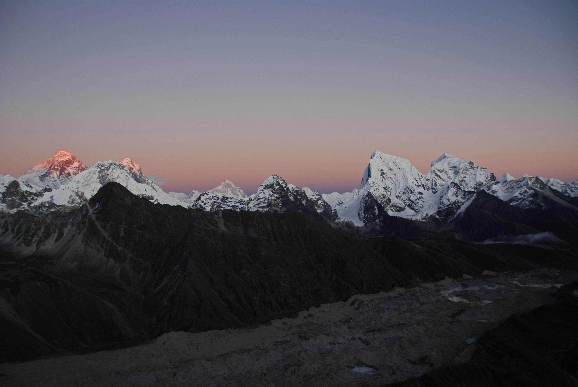 10 Gokyo Ri 08-1 Everest, Nuptse, Lhotse, Makalu, Cholatse, Tawache From Gokyo Ri Sunset Ends The last rays of the sun highlight Mount Everest and Lhotse, while a warm glow surrounds Nuptse, Makalu, Cholatse, and Taweche. The Nguzumpa Glacier is in shadow below.